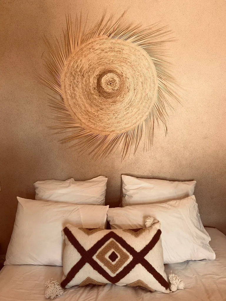 Chambre aux murs sable, suspensions en osier et tapis berbères