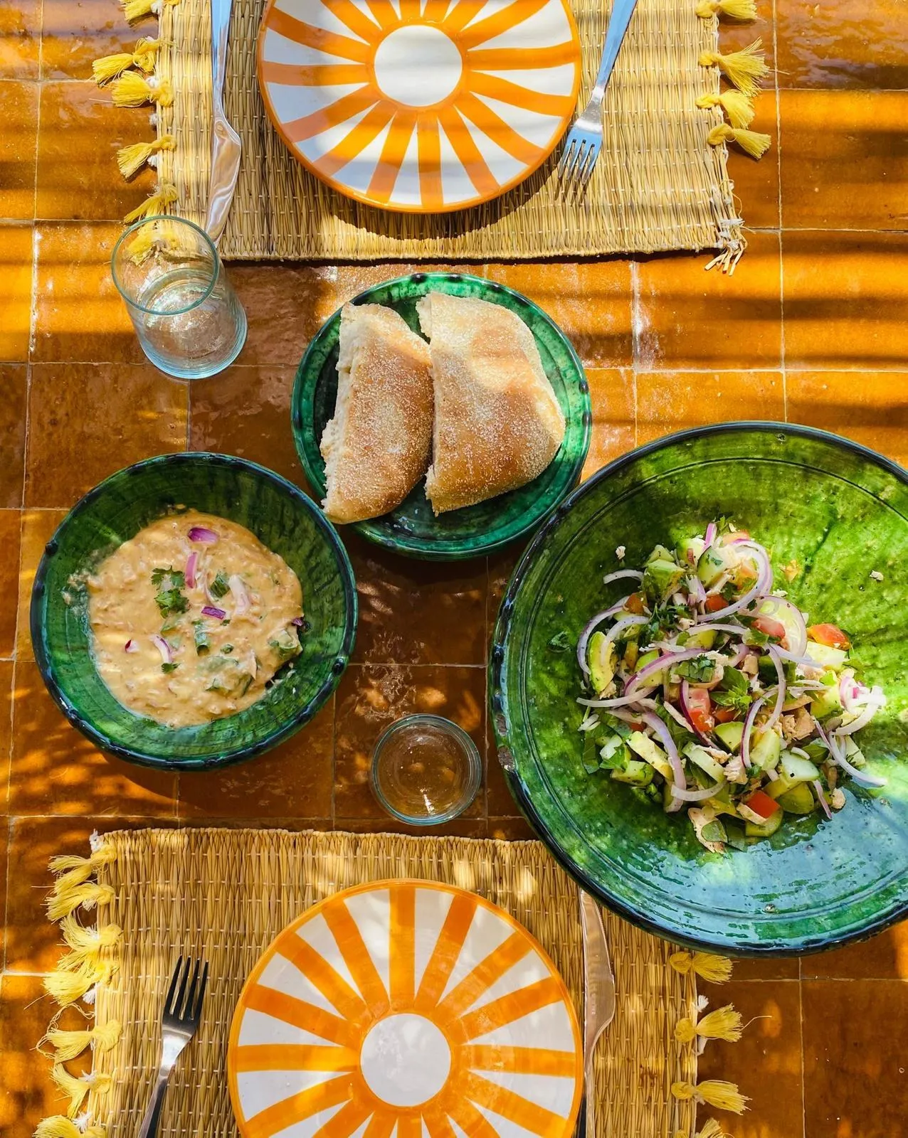 Table dressée : pain maison, dip et salade fraîche dans la vaisselle en céramique verte