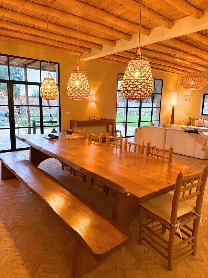 Grande table d'hôtes en bois massif dressée face à la cuisine ouverte