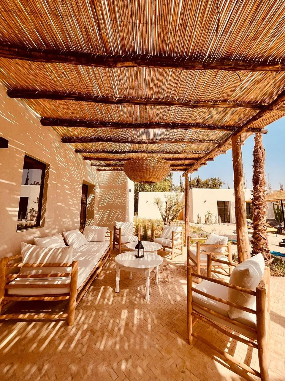 Salon extérieur sous la pergola de bois, face au jardin