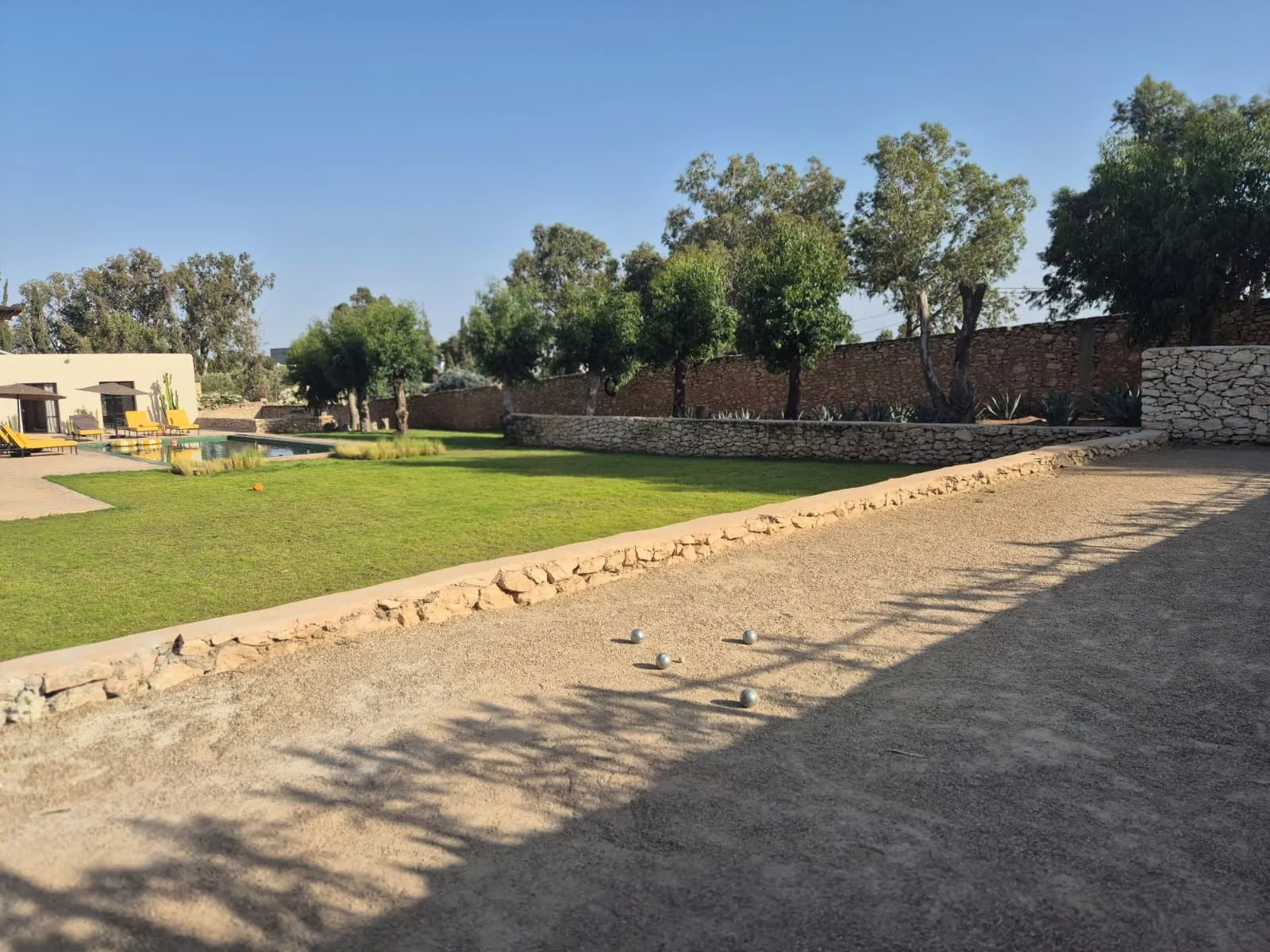 Terrain de pétanque paysagé, bordé de pelouse et de murets de pierre